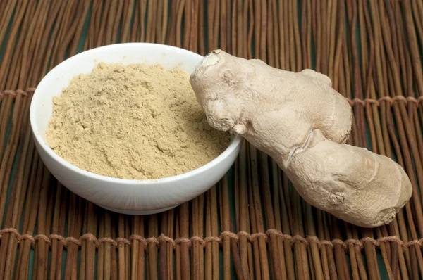 Powdered ginger in a bowl and whole ginger — Stock Photo, Image