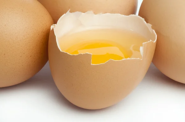 Целые яйца и еще одно разбитое наполовину сырое яйцо — стоковое фото
