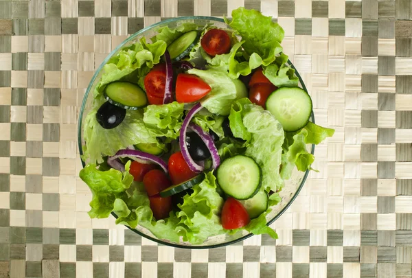 Salada em uma tigela de vidro em uma base de madeira — Fotografia de Stock