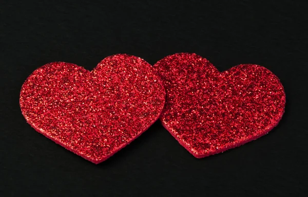 Corazones rojos brillantes sobre fondo negro — Foto de Stock