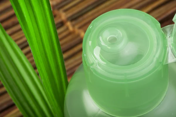 Green cosmetic bottle and leaf — Stock Photo, Image