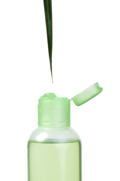 Зеленая косметическая бутылка и лист — стоковое фото