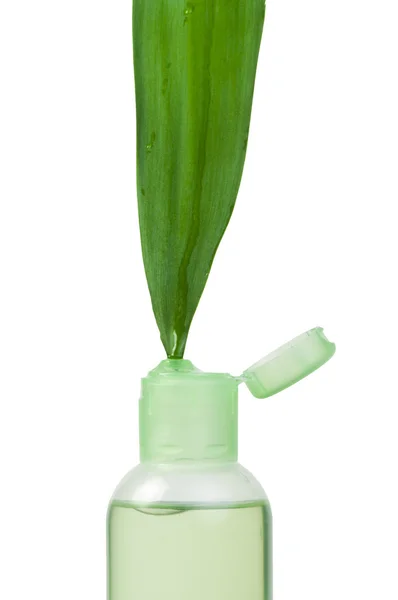 Green cosmetic bottle and leaf — Stock Photo, Image