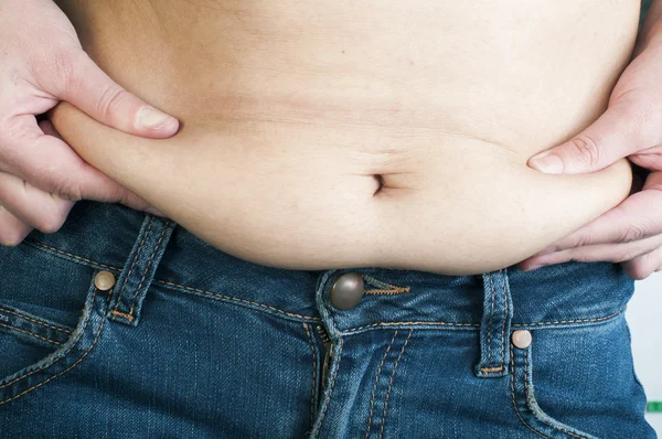 Woman pinching fat from her abdomen — Stock Photo, Image