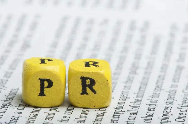 Word PR.Wooden cubes on magazine — Stock Photo, Image