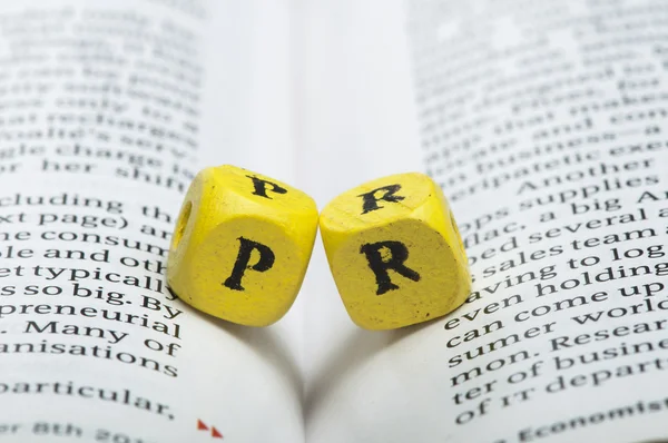 Word PR.Wooden cubes on magazine — Stock Photo, Image