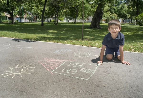 Bambino che disegna sole e casa su asfalto — Foto Stock