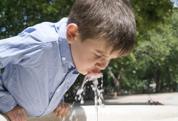 Kind drinking water uit een fontein — Stockfoto
