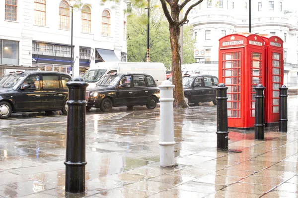 Rode telefoon cabines in Londen en vintage taxi.rainy dag. — Stockfoto
