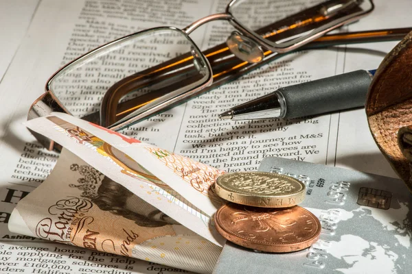 Brille, Münzen, Kreditkarten und Banknoten auf Zeitungen — Stockfoto