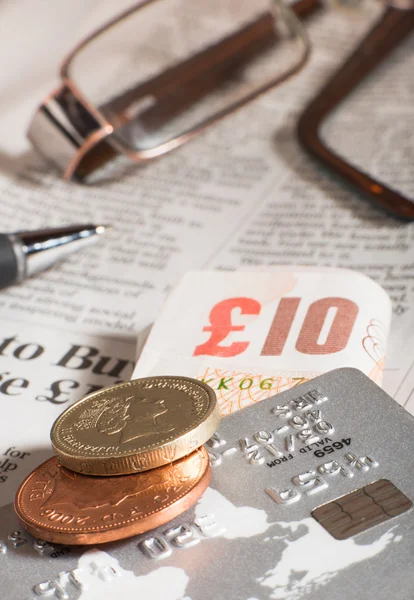 Glasögon, mynt, kort och sedlar på tidning — Stockfoto