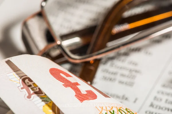 Glasses, coins, credit cards and banknotes on newspaper — Stock Photo, Image