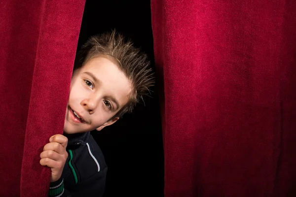 Child appearing beneath the curtain — Stockfoto