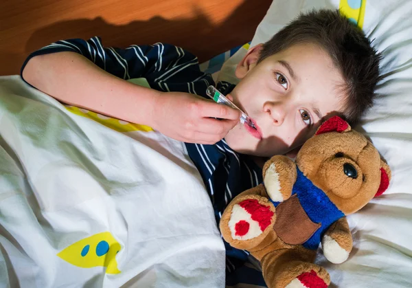 Enfant malade au lit avec ours en peluche — Photo