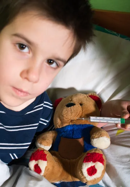 Oyuncak ayı ile yatakta hasta çocuk — Stok fotoğraf