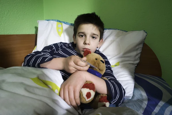 Хвора дитина в ліжку з плюшевим ведмедем — стокове фото