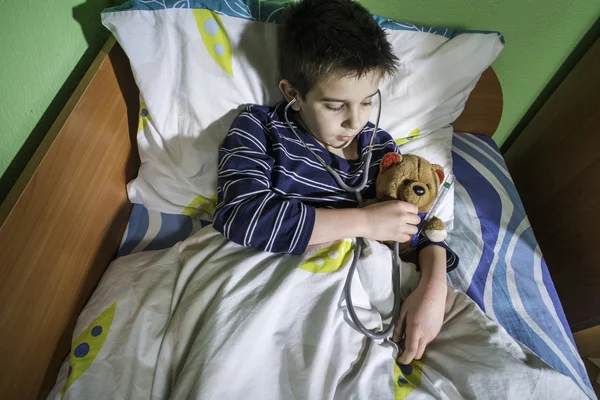 Criança doente na cama com ursinho de pelúcia — Fotografia de Stock