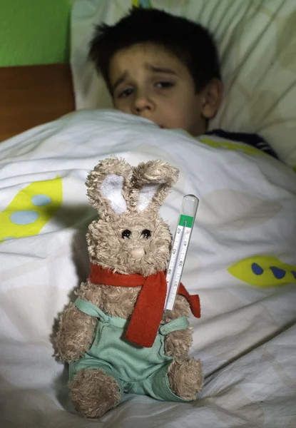 Enfant malade au lit avec ours en peluche — Photo