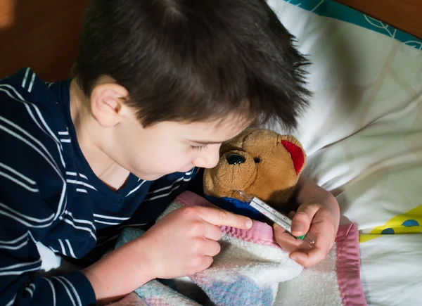 Enfant malade au lit avec ours en peluche — Photo