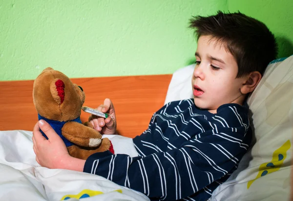 Bambino malato a letto con orsacchiotto — Foto Stock