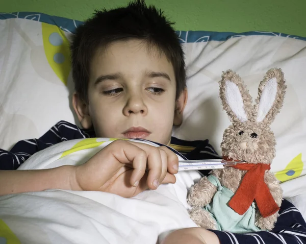 Criança doente na cama com ursinho de pelúcia — Fotografia de Stock