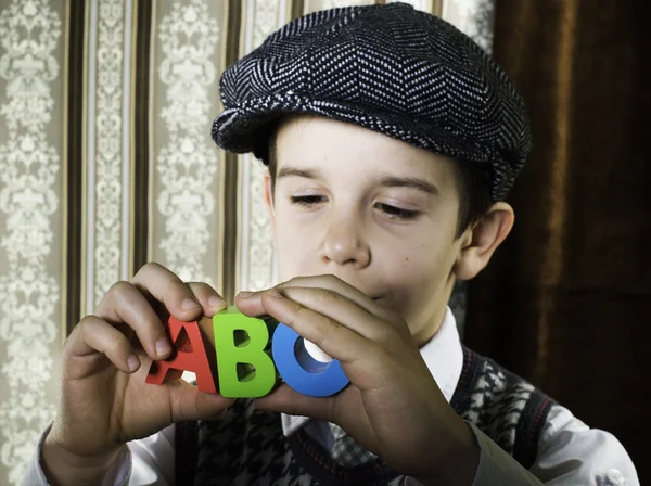 Kind in Vintage-Kleidung hält Buchstaben a b c — Stockfoto