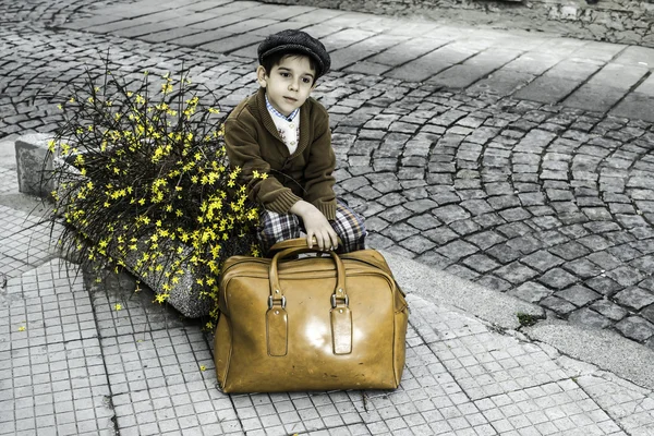 Niño en una carretera con bolso vintage — Foto de Stock