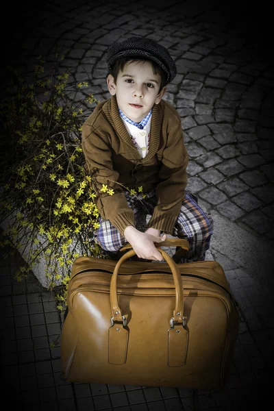 Niño en una carretera con bolso vintage Fotos De Stock