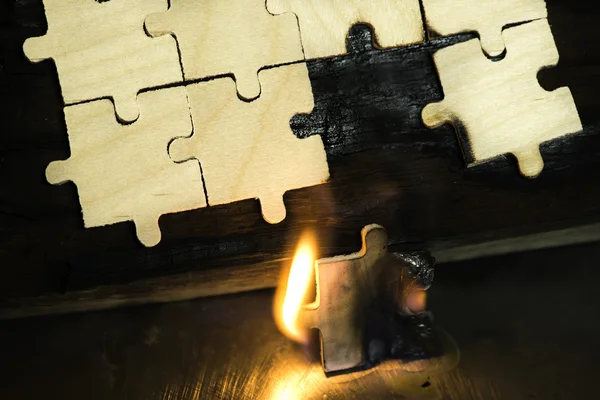 Bruciare puzzle di legno su sfondo scuro . — Foto Stock