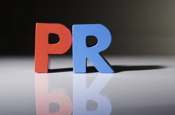 Multicolored word PR made of wood. — Stock Photo, Image