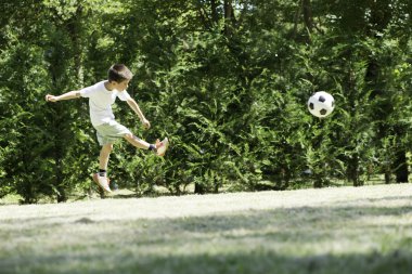 bir stadyumda futbol oynayan çocuk