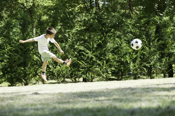 Ребенок играет в футбол на стадионе — стоковое фото