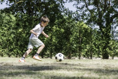 bir stadyumda futbol oynayan çocuk