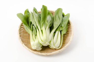 Beyaz arkaplanda bambu süzgeci üzerine Bok choy (Çin lahanası)