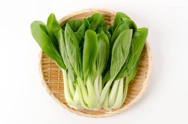 Beyaz arkaplanda bambu süzgeci üzerine Bok choy (Çin lahanası)