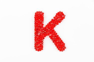 Beyaz zemin üzerinde kırmızı boncuklar alfabesi K