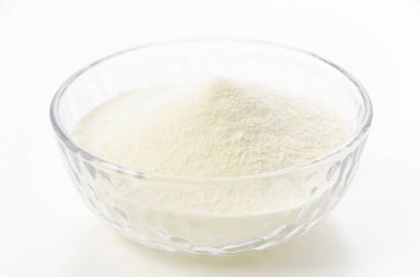 Beyaz arka planda cam kasede yağsız süt tozu