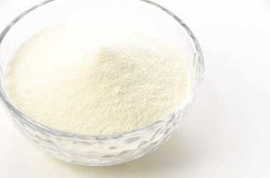 Beyaz arka planda cam kasede yağsız süt tozu