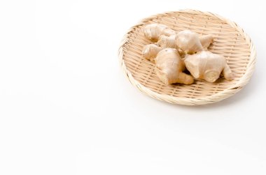 Beyaz arka planda bambu eleğinde taze zencefil. 