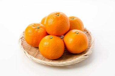 Beyaz arka planda bambu süzgeci üzerine taze Citrus iyo Japon narenciye meyveleri Iyokan