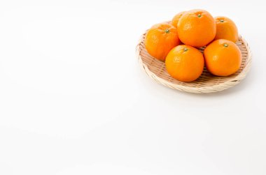 Beyaz arka planda bambu süzgeci üzerine taze Citrus iyo Japon narenciye meyveleri Iyokan