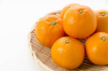 Beyaz arka planda bambu süzgeci üzerine taze Citrus iyo Japon narenciye meyveleri Iyokan