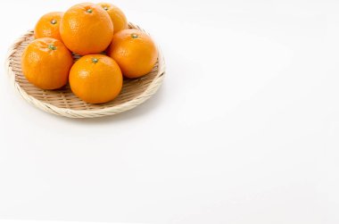 Beyaz arka planda bambu süzgeci üzerine taze Citrus iyo Japon narenciye meyveleri Iyokan