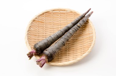 Beyaz arka planda bambu elek üzerinde siyah havuç