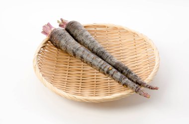 Beyaz arka planda bambu elek üzerinde siyah havuç