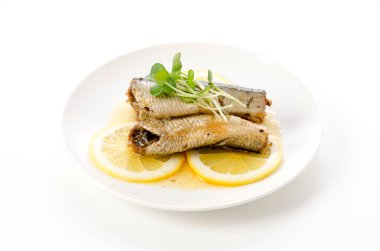 Beyaz tabakta dilimlenmiş limonlu sardalyalar. 