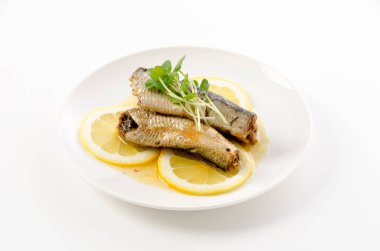 Beyaz tabakta dilimlenmiş limonlu sardalyalar. 