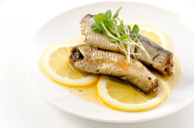 Beyaz tabakta dilimlenmiş limonlu sardalyalar. 