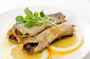 Beyaz tabakta dilimlenmiş limonlu sardalyalar. 