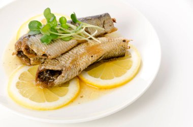 Beyaz tabakta dilimlenmiş limonlu sardalyalar. 